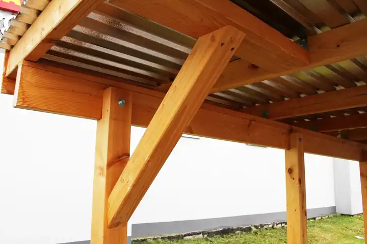 Structure de carport en bois vue de dessous : poteau, poutre et jambe de force à 45 degrés