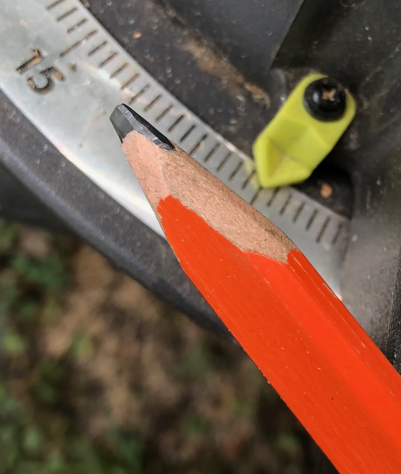 Crayon de charpentier taillé plat posé contre la lame graduée d'un mètre ruban