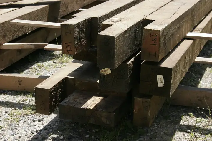Pile de poutres en bois de section carrée stockées dehors