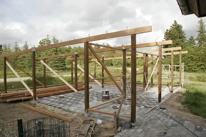 Ossature en bois d'un carport en cours de montage : poteaux, poutres et contreventements