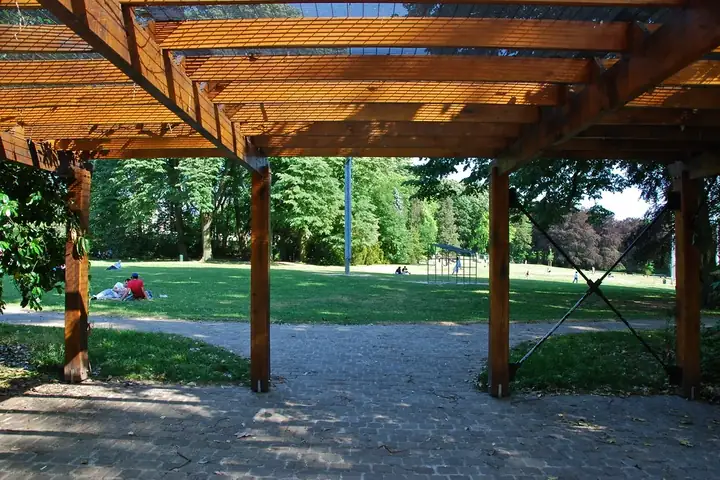 Grande pergola en bois à chevrons apparents dans un parc de Bruxelles