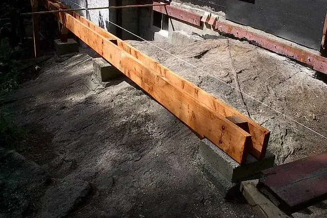 Poutre de terrasse en bois posée sur des appuis au-dessus d'une dalle, en cours de chantier