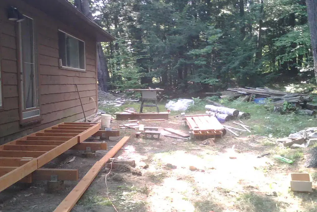 Solivage d'une terrasse en bois posé le long d'une maison, avant la pose des lames