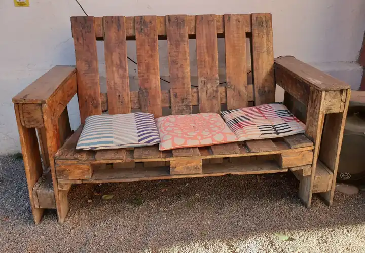 Banquette en palettes de bois avec accoudoirs et coussins