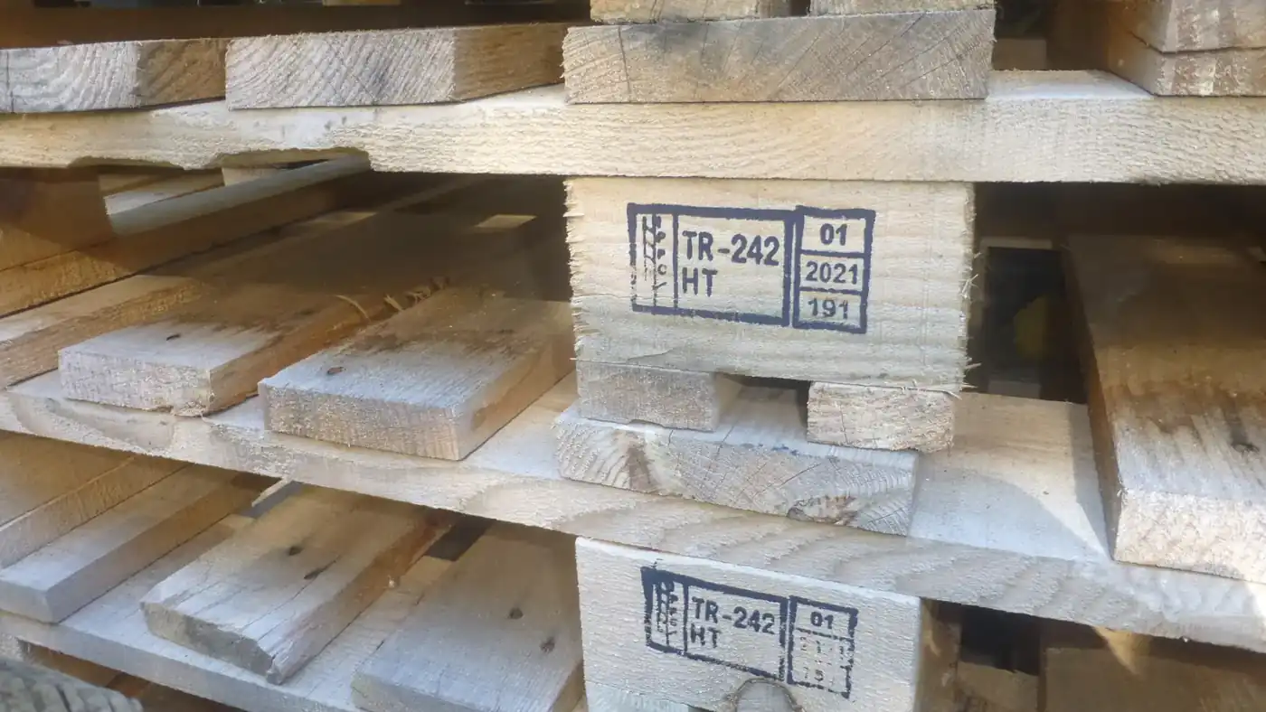 Pile de palettes en bois dont les dés portent le marquage IPPC avec la mention HT