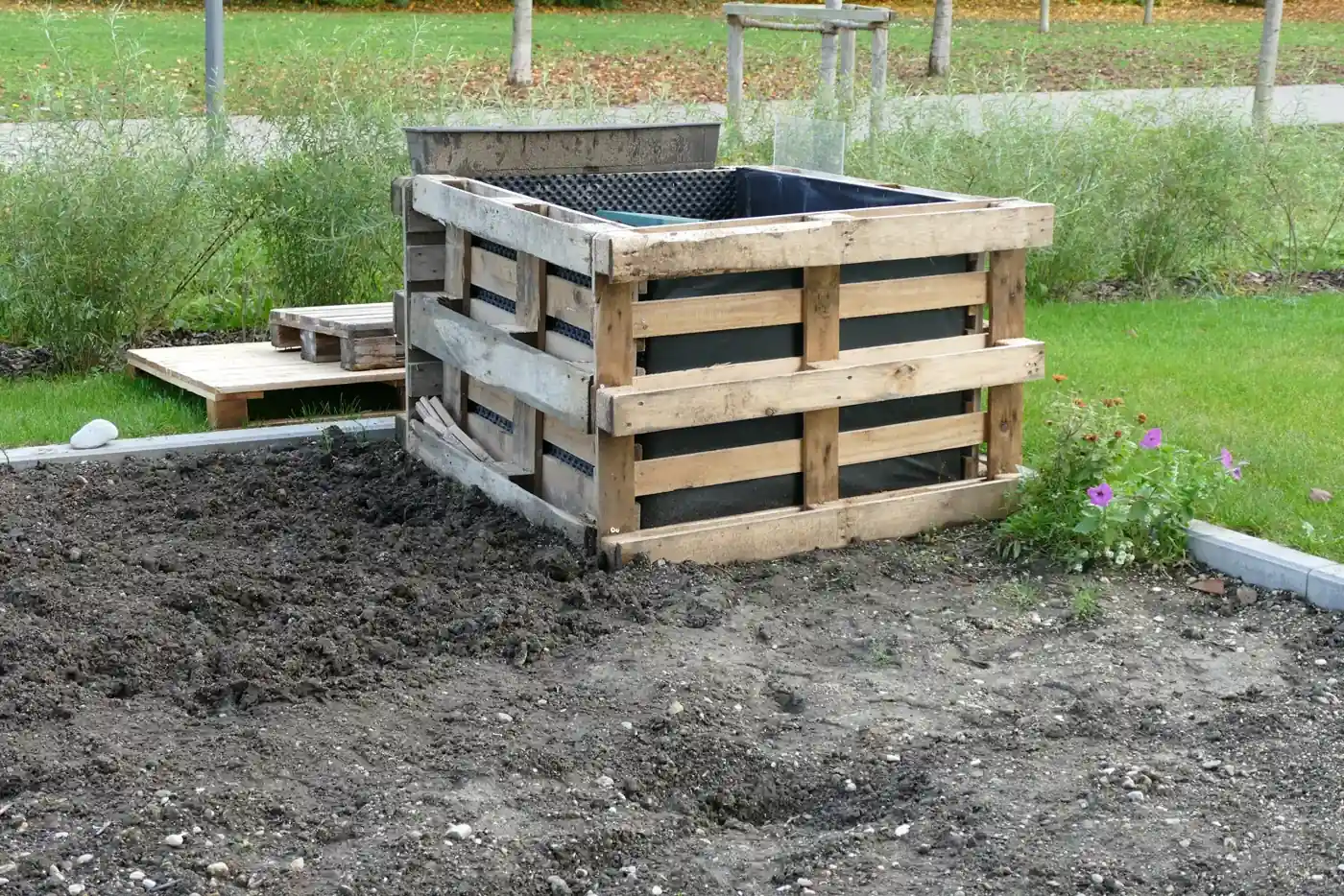 Bac de jardin fait de palettes EUR empilées et doublées d'une bâche, dans un jardin