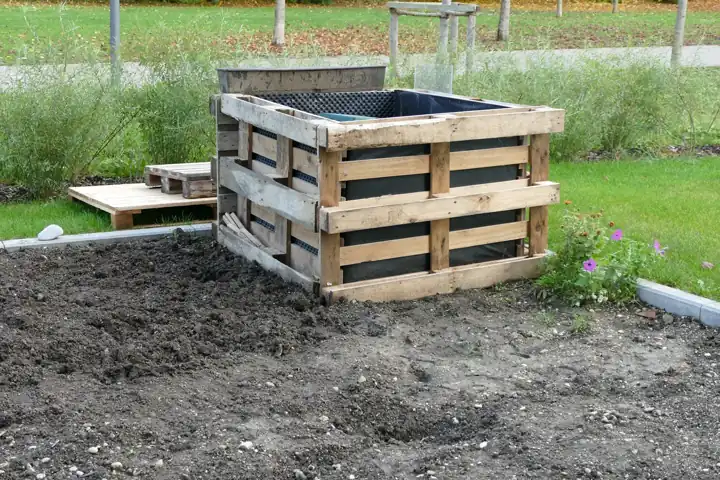 Bac de jardin fait de palettes EUR empilées et doublées d'une bâche, dans un jardin